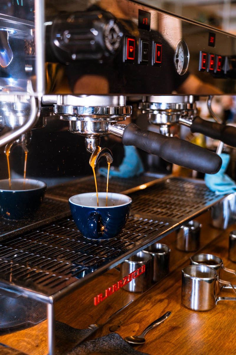 Espresso loopt uit de koffiemachine in een blauw kopje.